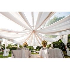 the inside of a tent with tables and chairs set up for an outdoor wedding reception