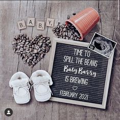 baby announcement with booties and coffee beans on wooden table next to sign that says time to spill the beans