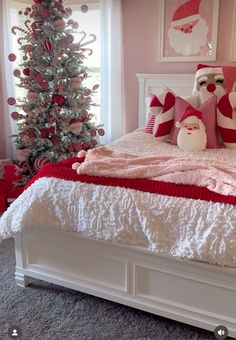 a white bed topped with pillows next to a christmas tree in a pink and white bedroom