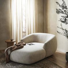 a white chair sitting in front of a window next to a table with a plant on it