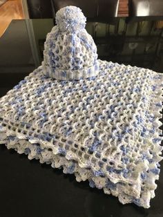 a crocheted blue and white blanket sitting on top of a table next to a black chair