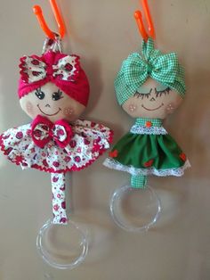 two little dolls are hanging from hooks on the wall, one is wearing a green and white dress