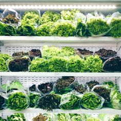 several shelves filled with lettuce and other vegetables in plastic bags on top of each shelf