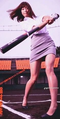 a woman holding a baseball bat on top of a field