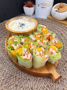 a wooden platter filled with sushi rolls and sauce on top of a table