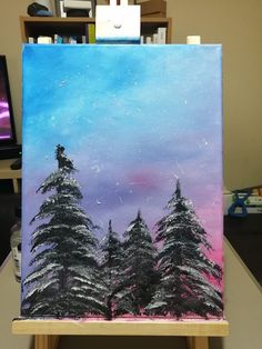 an easel with a painting on it that has some trees in the background and purple sky