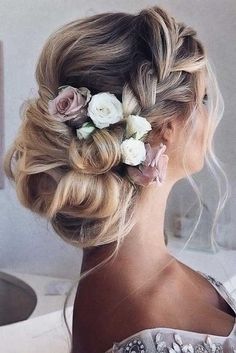 a woman with blonde hair and flowers in her hair is wearing a flowered updo