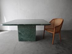 a green marble table and chair sitting next to each other in an empty room with white walls