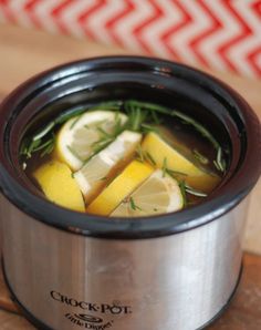 a crock pot filled with lemon slices and herbs