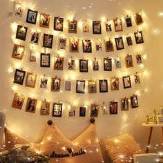 there are many pictures hanging on the wall with lights around them and some decorations below