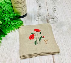 two wine glasses sitting on top of a table next to a napkin with red flowers