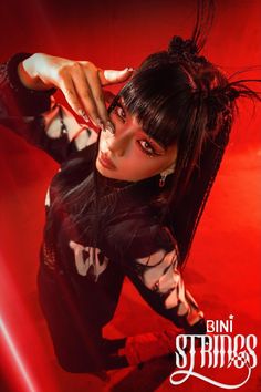 a woman with long black hair and piercings on her head is posing in front of a red background