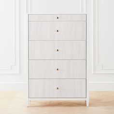 a white chest of drawers sitting on top of a hard wood floor next to a wall