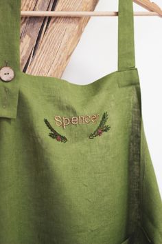 a green apron hanging on a clothes rack with the word spencer embroidered on it's side