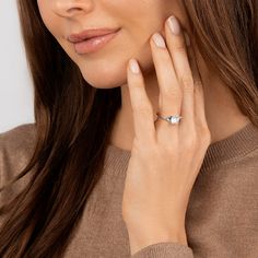 a woman wearing a diamond ring on her left hand and looking at the camera while she is