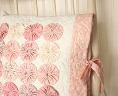 a pink and white decorative pillow on a bed