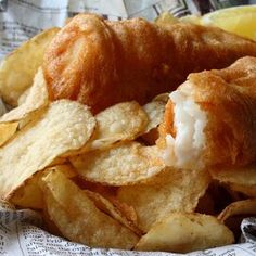 a close up of a plate of food with potato chips and lemon wedges on the side