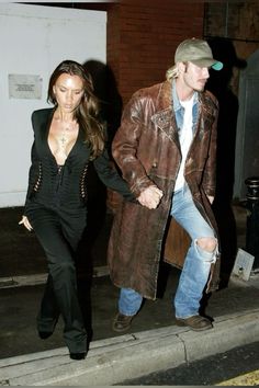 a man and woman walking down the street holding hands