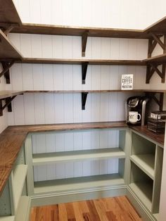 a coffee maker and some shelves in a room with wood flooring on the walls