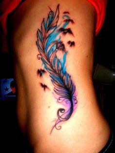 a woman's stomach with a blue and black feather tattoo on her lower back