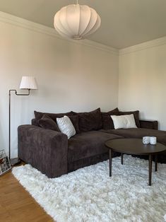 a living room with a couch, coffee table and lamp on the wall above it