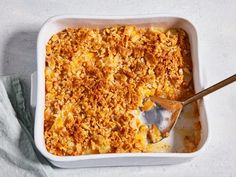 a casserole dish with a wooden spoon in it on a white tablecloth