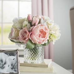 a vase filled with flowers sitting on top of a table next to a framed photo