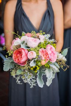 a bridesmaid holding a bouquet of pink roses and greenery