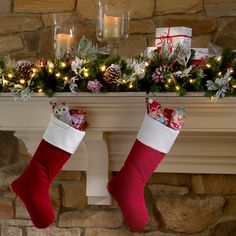 two stockings hanging from a mantel decorated with christmas decorations and lights, next to candles