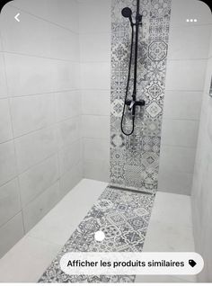 a bathroom with white tiles and black fixtures on the shower wall, along with tile flooring