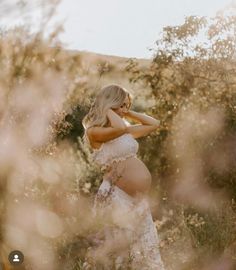 a pregnant woman in a white dress is posing for the camera with her hands on her hips