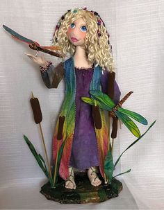 a figurine is holding scissors in her hand and standing next to some plants