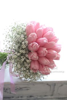 a bouquet of pink tulips and baby's breath in front of a window