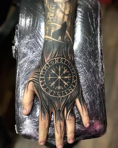 a person with a tattoo on their arm holding a clock and compass in his hand