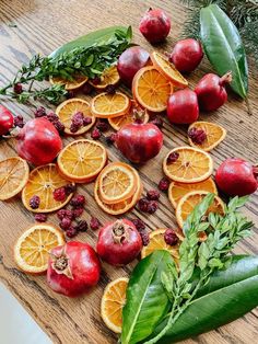 oranges and pomegranates cut up on a cutting board with leaves