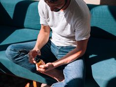 a man sitting on top of a blue couch holding a cell phone in his hand