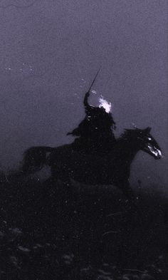 black and white photograph of a man on a horse in the foggy night sky