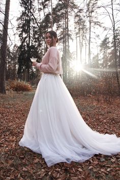 a woman in a wedding dress standing in leaves