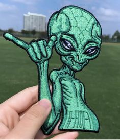 someone is holding up a green alien patch