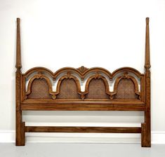 a wooden bed frame with wicker headboard and foot board on white wall background