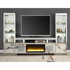 an entertainment center with a large television and fireplace in the middle, surrounded by glass shelves