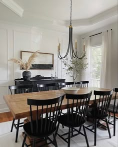 a dining room table with black chairs and a chandelier