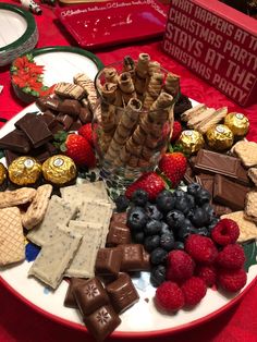 a plate full of chocolates, raspberries and strawberries on a table