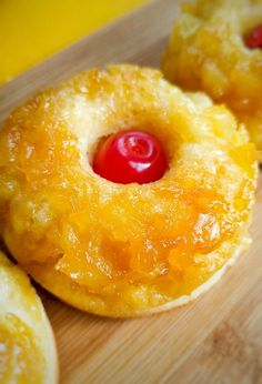 pineapple upside down donuts with a cherry in the middle on a cutting board