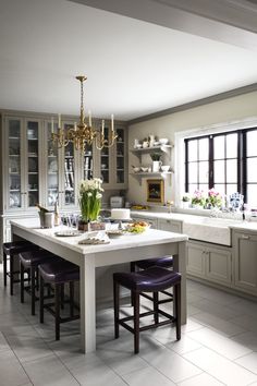 a large kitchen with an island table surrounded by purple stools and white cabinets,