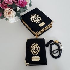 two black and gold books are next to a bouquet of flowers on a white table