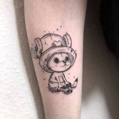 a small tattoo on the leg of a person wearing a hat and holding a pipe