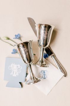 three silver wine goblets sitting on top of a table next to a napkin