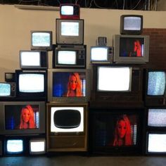 several televisions stacked on top of each other in front of a wall full of tv screens