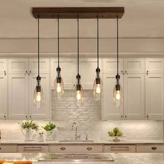 a kitchen filled with lots of counter top space and lights hanging from the ceiling above it